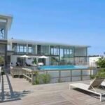 A Fire Island glass house drew 350+ viewers at .25 million but no buyer; after .255 million in cuts, its .995 million ask is still nearly .3 million above Cherry Grove’s record sale