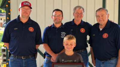 An 8-year-old Indiana boy spotted a smoking camper trailer and alerted people nearby before it caught fire; he was honoured with Department Patch and Certificate of Recognition for preventing a larger emergency